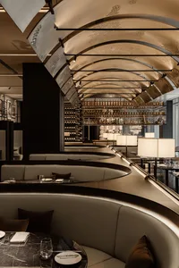 Modern restaurant interior with a long bar, wine bottles, and comfortable seating for guests