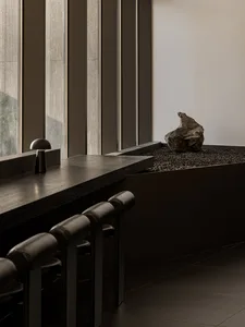 A minimalist kitchen with a countertop, a rock on display, and two chairs near a window