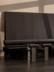 Empty room with a black leather bench and wooden wall, two chairs, and well-lit atmosphere