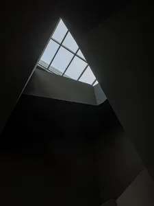 A small, triangular room with a skylight in the ceiling, allowing sunlight to create a bright spot on the wall