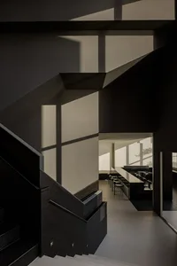 Dark interior space with a black staircase, chairs, and industrial-style decor