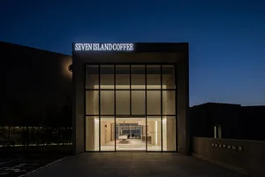 A warm and inviting coffee shop with a stone facade, glass door, and comfortable seating areas, perfect for socializing and relaxation