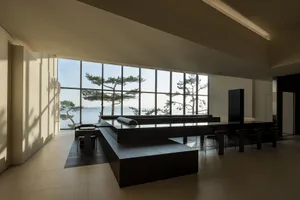 Open modern living space with black countertops, a black table, and natural light from a large window with a view of trees outside