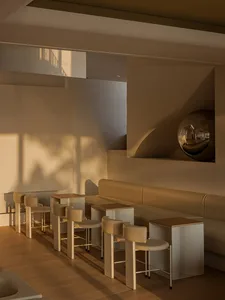 A well-lit living area with a couch, chairs, tables, and a large mirror, featuring a combination of white and brown elements, with a warm and inviting atmosphere