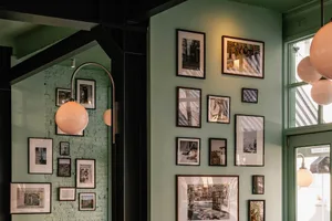 A restaurant wall with a gallery of framed pictures in various sizes, arranged to create a decorative display on a green wall