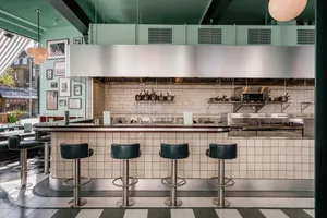 Industrial-style restaurant kitchen with a counter, stools, appliances, and organized storage