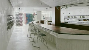 A casual bar area with a counter, sink, chairs, and bottles, surrounded by scattered cups in a restaurant setting