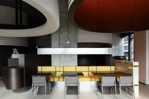 Modern restaurant interior with concrete walls, wooden furniture, and ample seating options