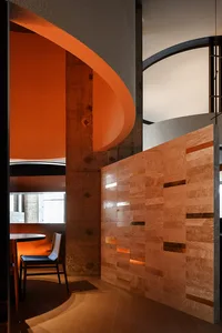 Warm and inviting room with orange lighting, a circular wall design, and a dining table and two chairs