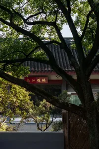 A traditional Asian building with a red roof, surrounded by trees, featuring a pagoda-style roof and wooden structure