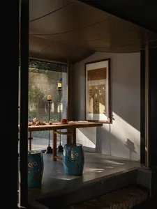 Dining space with Asian-inspired decor, a blue vase, and a potted plant, surrounded by chairs in a warm and inviting atmosphere