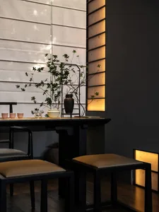Elegant dining space with a black table, four chairs, potted plants, and three cups, creating a warm and inviting atmosphere