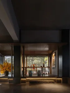 A modern dining room with a black and white color scheme, wooden elements, and a well-lit atmosphere, featuring a dining table and chairs with vases on the table