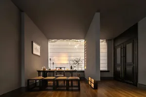 Empty modern living room with a dining table, chairs, potted plants, and decorative bottles, creating a cozy atmosphere