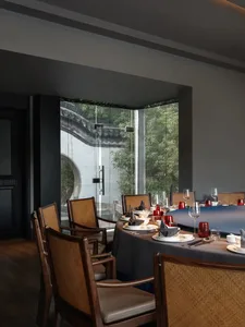 Elegant Asian restaurant interior with a large dining table set with various items and vases, surrounded by chairs