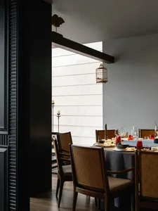 A dining area in a restaurant with a large table set for guests, surrounded by chairs and decorated with vases, creating a sophisticated and inviting atmosphere