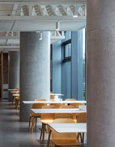 A modern dining area with multiple white tables and chairs, cups, and a spacious atmosphere