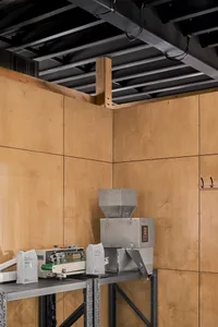 Industrial workspace with a large machine and smaller machines on either side, surrounded by wood panel walls