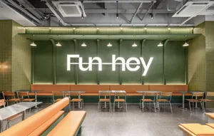 A modern restaurant with a green wall, dining tables, and benches, creating a casual atmosphere for guests