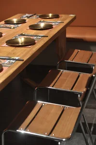 Warm and inviting dining area with a long wooden table and chairs, set for a meal with several bowls on the table