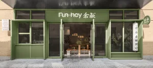 An inviting Asian restaurant with green walls, wooden furniture, and potted plants, creating a comfortable dining atmosphere
