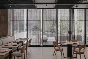 A modern restaurant interior with multiple tables and chairs, clean and inviting atmosphere, white walls, and a neutral color scheme