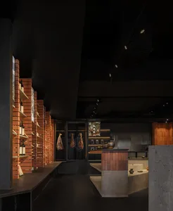 Dark and moody restaurant kitchen with industrial appliances, bottles, and functional design elements