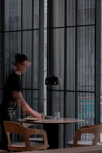 A warm and inviting dining area with a wooden table, chairs, and wine glasses, suggesting a meal or gathering