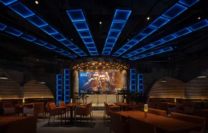 A cozy restaurant bar with wooden accents, chairs, and tables, featuring bottles and a warm atmosphere
