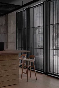 A well-lit interior space with two wooden stools and a chair on a hardwood floor, near a window