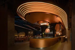 A modern restaurant interior with a golden bar counter, comfortable seating, and well-lit dining area