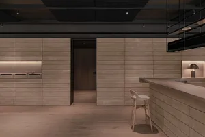 Modern kitchen with wooden walls and floors, a large countertop, and a sink, featuring two chairs in a clean and well-organized space