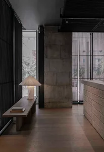 A warm and inviting study space with a wooden bench near a window, a lamp, and a book, featuring natural and artificial lighting