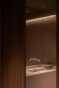 Modern bathroom with a sink and shower area, featuring a wooden wall and minimalist design