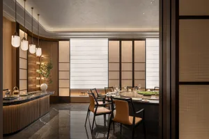 A dining area in a restaurant with a large table, multiple chairs, and fine dinnerware, set in a sophisticated and inviting atmosphere
