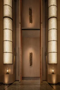 A well-lit hallway with wooden walls and ceiling, featuring two large wooden doors and a sense of depth and dimension