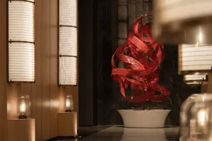 A modern decorative art piece featuring a red ribbon sculpture in a white bowl on a marble countertop, creating an elegant and sophisticated atmosphere