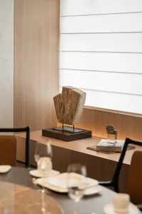 溫馨 inviting 的餐廳空間，配有木桌、椅子、酒杯、一本書與雕塑，營造時尚舒適的環境