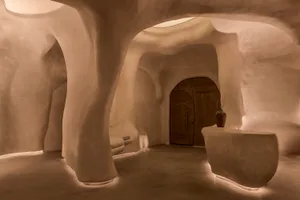 Cozy interior space with a large archway, sink area, bench, and potted plants, creating a welcoming atmosphere