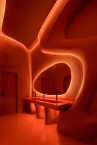 A bathroom with two sinks, red walls, and a bottle near one of the sinks, giving a clean and well-maintained appearance