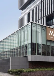 A modern building with a large glass front, showcasing its interior design and allowing natural light to enter the space, creating a bright and inviting atmosphere
