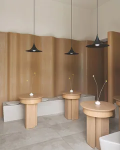 Interior design showroom with wooden tables and chairs, well-lit and decorated with a vase on one of the tables
