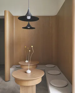 Warm and cozy interior design with wooden walls and floors, featuring three round tables with flower vases