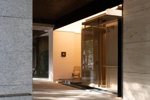 Modern entrance with a glass door, a large window, and two chairs for seating, set in a well-lit and functional space