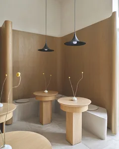 A well-lit room with wooden tables and chairs, white vases, and a warm atmosphere