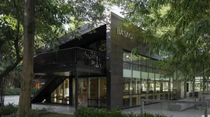 A wooden building with a large glass window, surrounded by chairs in a calm and inviting public space with natural light