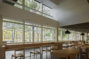 Bright modern restaurant interior with large windows, dining tables, and chairs, creating a welcoming atmosphere