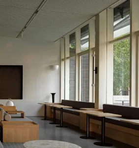 Modern restaurant interior with wooden tables and chairs, warm atmosphere, and comfortable seating options