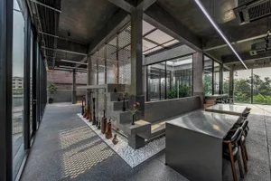 Open living area with natural light, potted plants, chairs, and dining tables in a modern space with clean lines and minimalistic decor