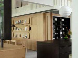Open concept living area with wooden floors and walls, featuring chairs and books, creating a warm and inviting atmosphere